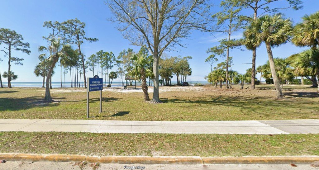 Port St. Joe Waterfront Park sign with palms and bay views beyond